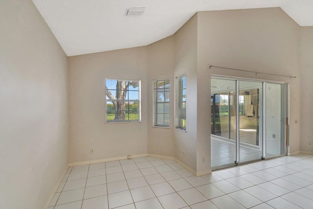 tiled spare room featuring high vaulted ceiling