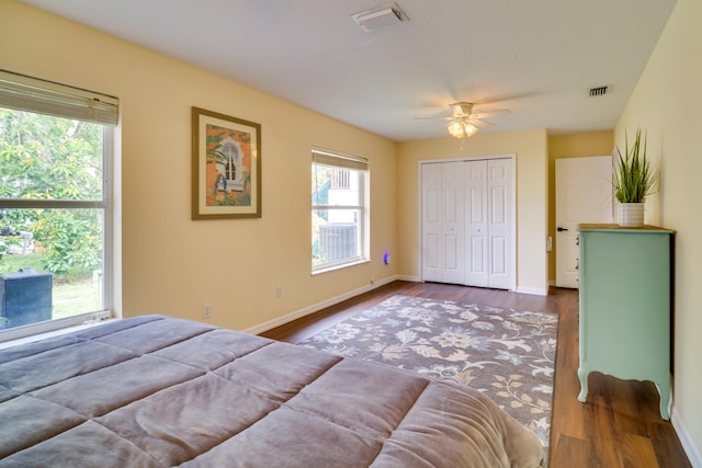 bedroom with a closet, visible vents, baseboards, and wood finished floors