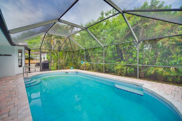 outdoor pool with glass enclosure and a patio area