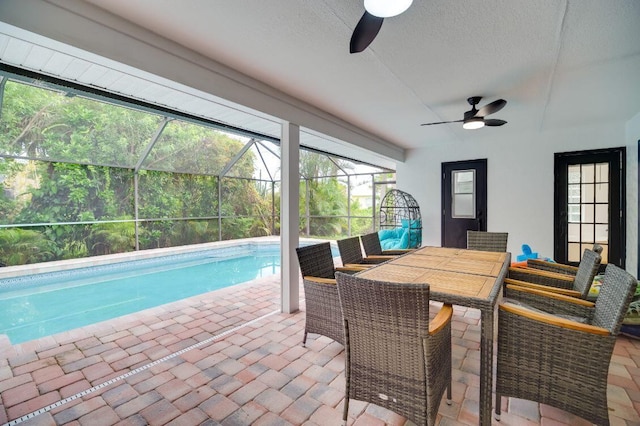 outdoor pool featuring ceiling fan, a patio, outdoor dining area, and glass enclosure