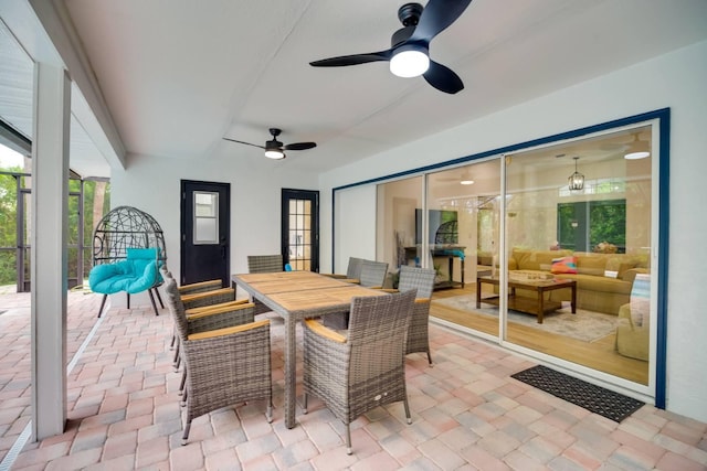 view of patio / terrace featuring outdoor dining space, glass enclosure, ceiling fan, and an outdoor living space