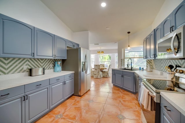 kitchen featuring tasteful backsplash, appliances with stainless steel finishes, gray cabinetry, a sink, and light tile patterned flooring