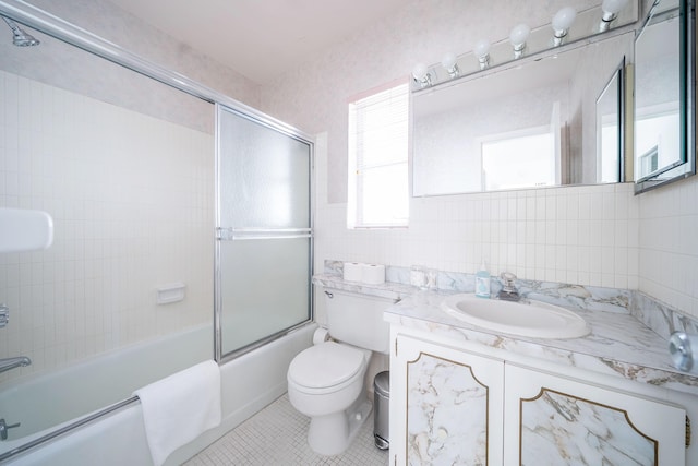 full bathroom with toilet, bath / shower combo with glass door, tile walls, tile patterned floors, and vanity