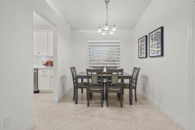 dining space with lofted ceiling, light tile patterned floors, and a chandelier