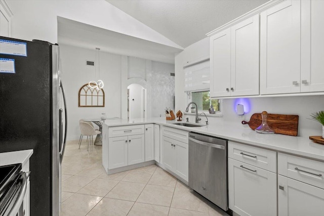 kitchen with sink, light tile patterned floors, appliances with stainless steel finishes, white cabinets, and vaulted ceiling