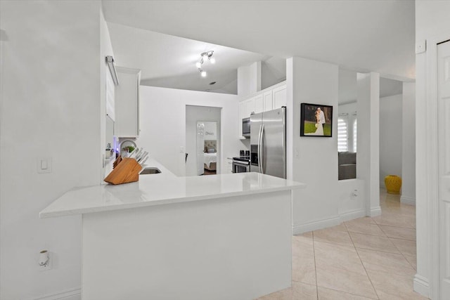 kitchen with appliances with stainless steel finishes, light tile patterned floors, white cabinets, and kitchen peninsula