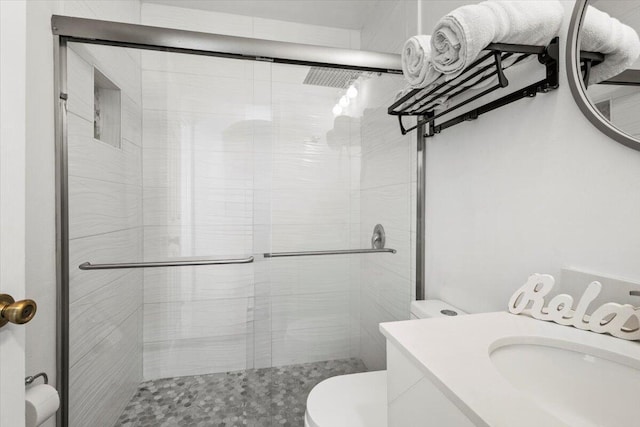 bathroom featuring vanity, toilet, and a shower with door