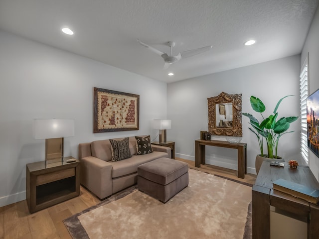 living room featuring hardwood / wood-style flooring, a textured ceiling, and ceiling fan