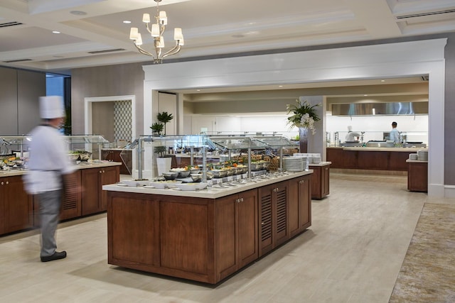 kitchen with decorative light fixtures, a chandelier, beamed ceiling, and an island with sink