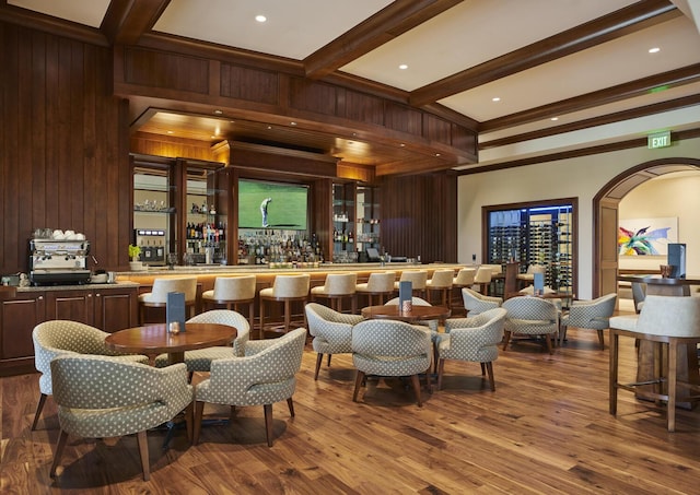 bar featuring hardwood / wood-style floors, wood walls, and beamed ceiling