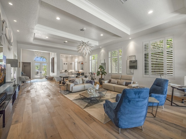 living room featuring light hardwood / wood-style floors, french doors, a wealth of natural light, and a raised ceiling