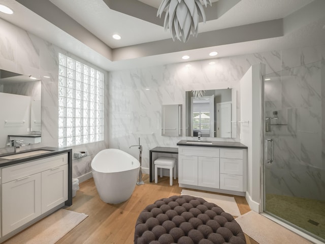 bathroom with hardwood / wood-style floors, vanity, tile walls, and shower with separate bathtub