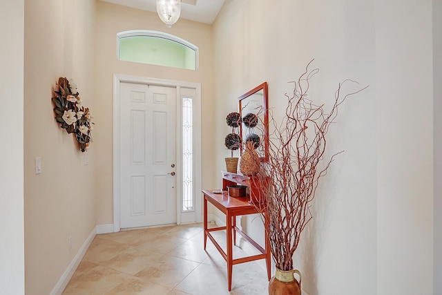 entryway with a towering ceiling, plenty of natural light, and light tile patterned floors