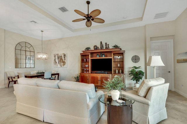 living room with ceiling fan with notable chandelier and a raised ceiling