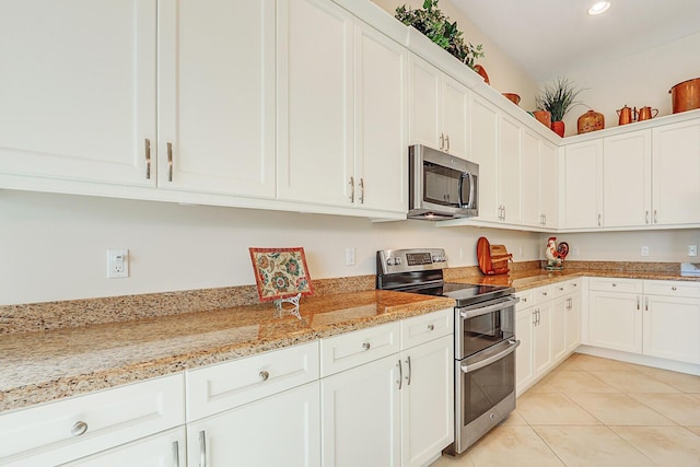 kitchen featuring white cabinetry, light stone countertops, light tile patterned floors, and stainless steel appliances