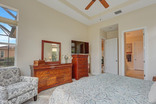 carpeted bedroom with multiple windows, a tray ceiling, and ceiling fan