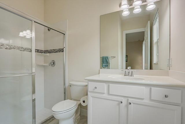 bathroom featuring vanity, a shower with shower door, and toilet