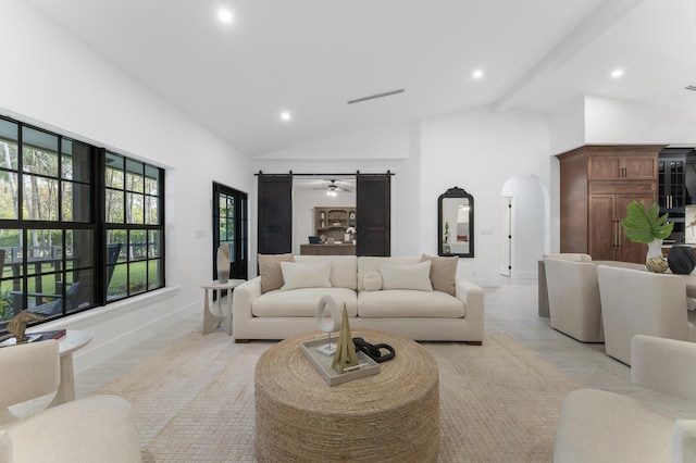 living room featuring light hardwood / wood-style flooring, beam ceiling, high vaulted ceiling, and a barn door