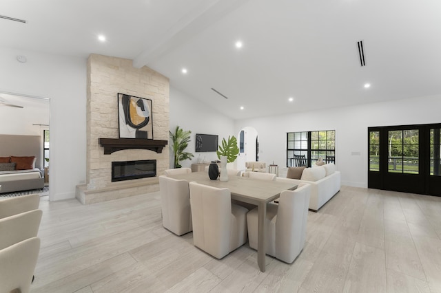 living room featuring light wood-type flooring, high vaulted ceiling, beam ceiling, and a fireplace