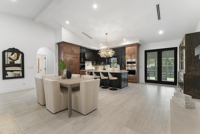 dining space with light hardwood / wood-style floors, lofted ceiling with beams, and a notable chandelier