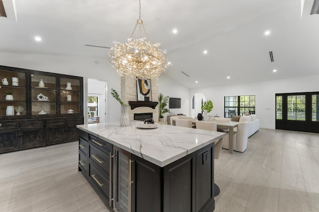 kitchen featuring a kitchen island, vaulted ceiling, hanging light fixtures, and light stone counters