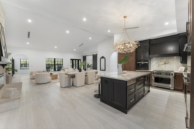 kitchen featuring high end range, a kitchen island, decorative light fixtures, backsplash, and a barn door