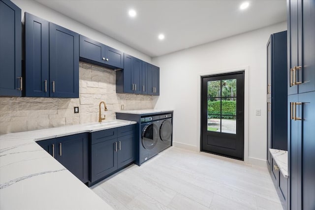 kitchen with sink, independent washer and dryer, tasteful backsplash, and blue cabinets