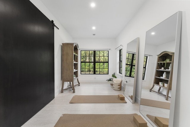 hall with a barn door and light hardwood / wood-style floors