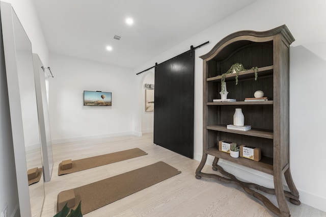 hall with light hardwood / wood-style floors and a barn door