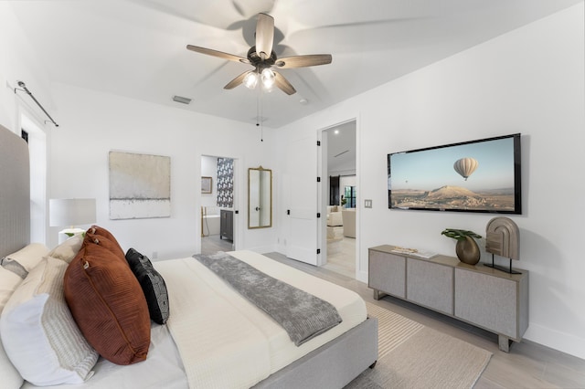 bedroom featuring ceiling fan, light hardwood / wood-style flooring, and ensuite bath