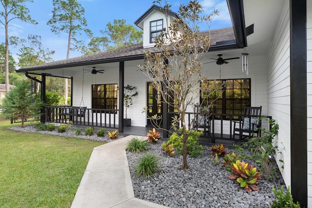 doorway to property featuring covered porch, a yard, and ceiling fan