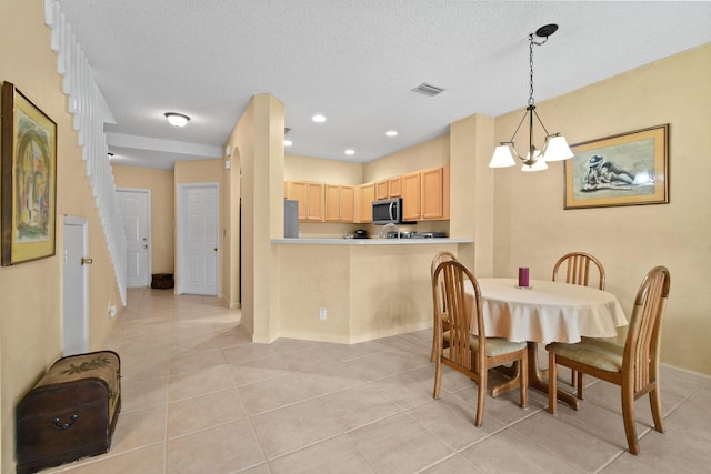 tiled dining space with an inviting chandelier and a textured ceiling