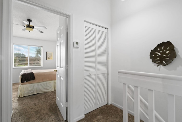 corridor featuring a textured ceiling and dark carpet