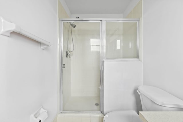 bathroom featuring toilet and a shower with door