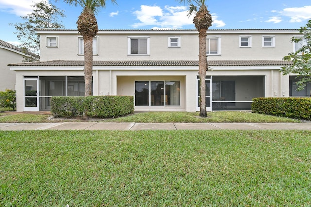 rear view of house featuring a yard and a sunroom