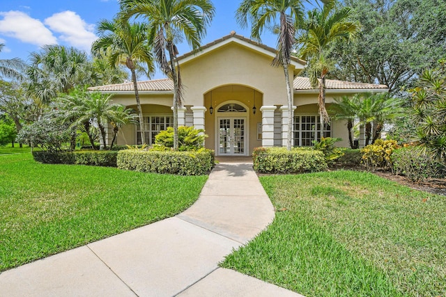 mediterranean / spanish home with a front yard and french doors