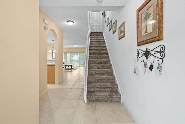 stairway with a textured ceiling and tile patterned flooring