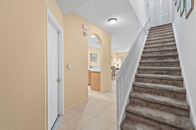 stairs with tile patterned floors and a textured ceiling