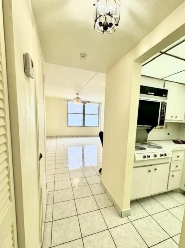 hallway with light tile patterned flooring and a notable chandelier