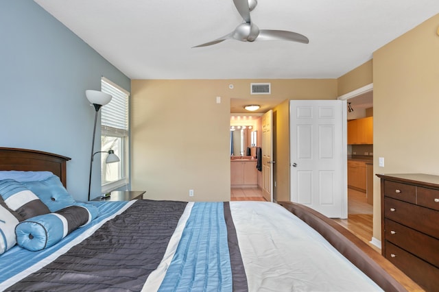 bedroom with ensuite bath, light hardwood / wood-style flooring, and ceiling fan