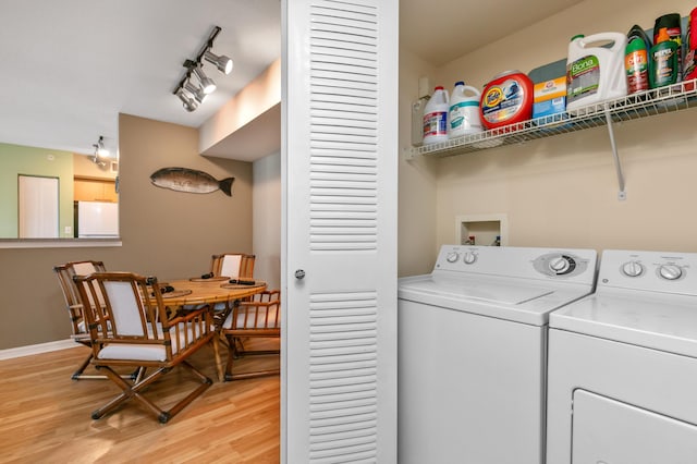 laundry area featuring separate washer and dryer, light hardwood / wood-style flooring, and rail lighting