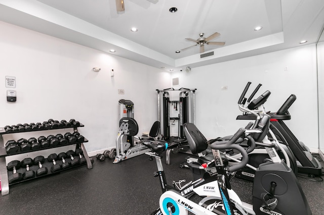 gym featuring ceiling fan and a tray ceiling