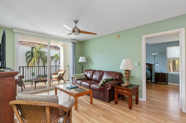 living room with ceiling fan, light wood-type flooring, and a wall of windows