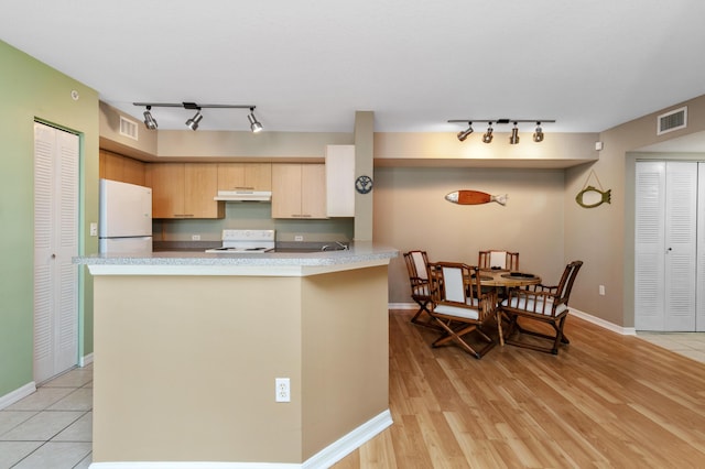 kitchen with light brown cabinetry, range, light wood-type flooring, white refrigerator, and kitchen peninsula