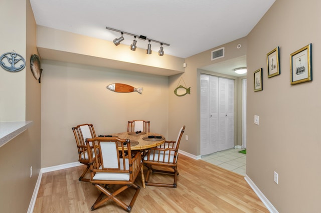 dining space with rail lighting and light hardwood / wood-style floors