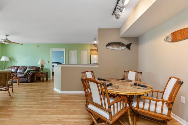 dining space with light hardwood / wood-style flooring, rail lighting, and ceiling fan