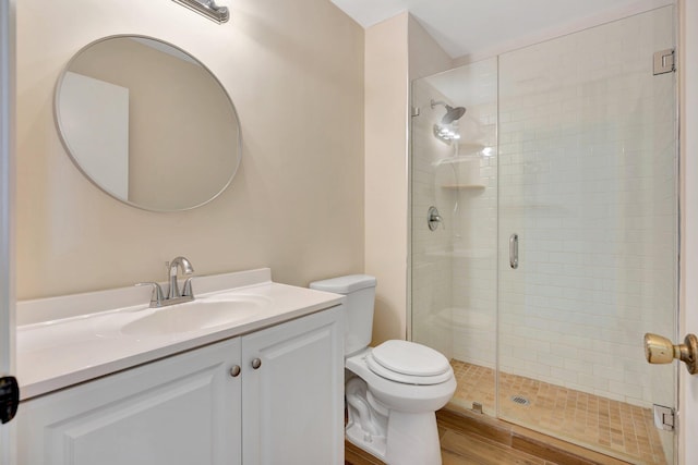 bathroom featuring vanity, a shower with door, and toilet