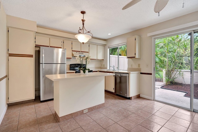 kitchen featuring sink, a kitchen island, pendant lighting, stainless steel appliances, and cream cabinets