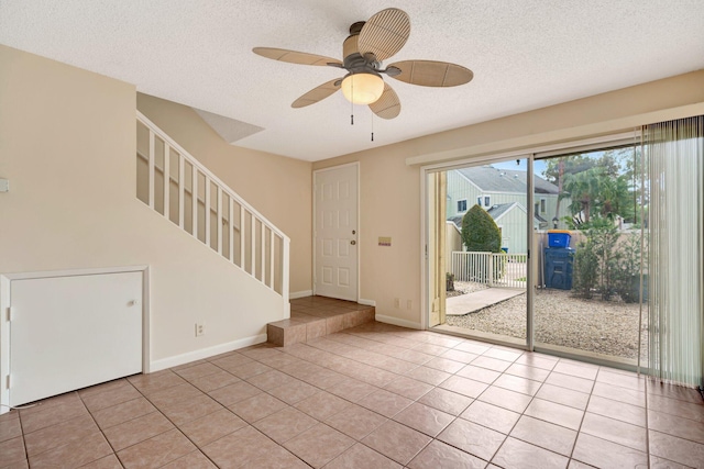 interior space with light tile patterned flooring, ceiling fan, and a textured ceiling