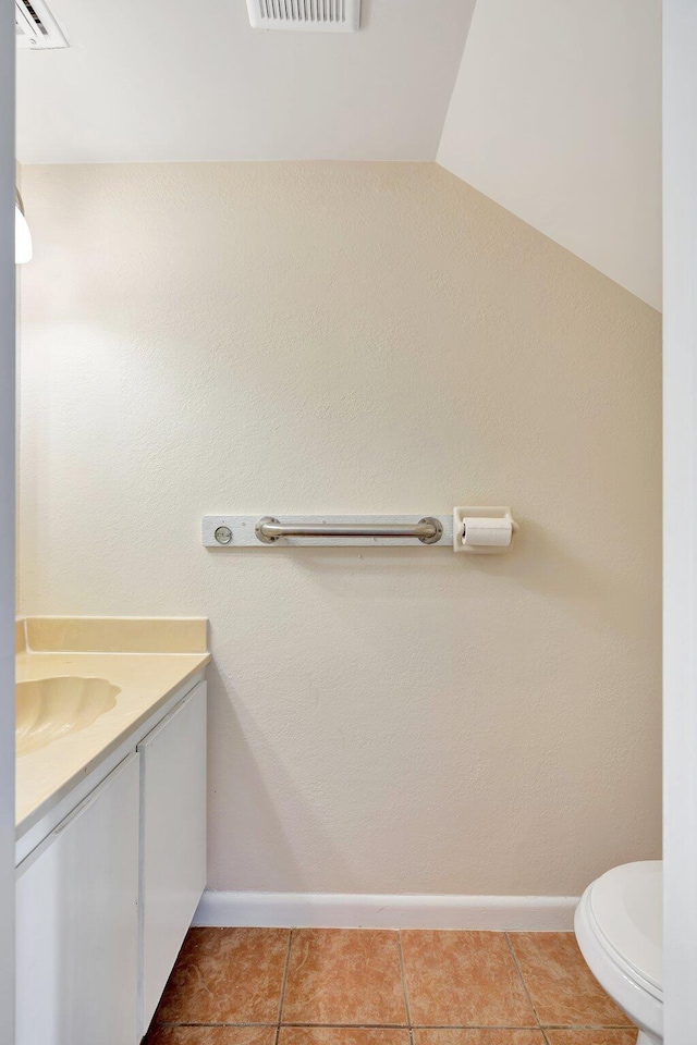 bathroom featuring lofted ceiling, vanity, toilet, and tile patterned flooring